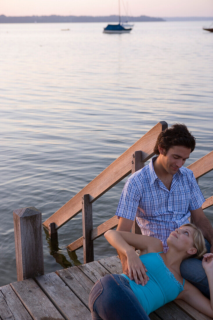 Young woman resting with head on man's lap, looking into each other's eyes