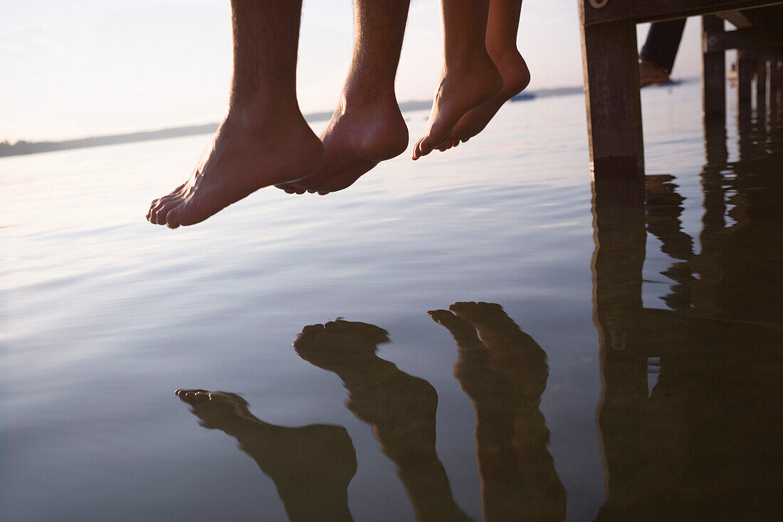 Bare feet dangling over lake, close up