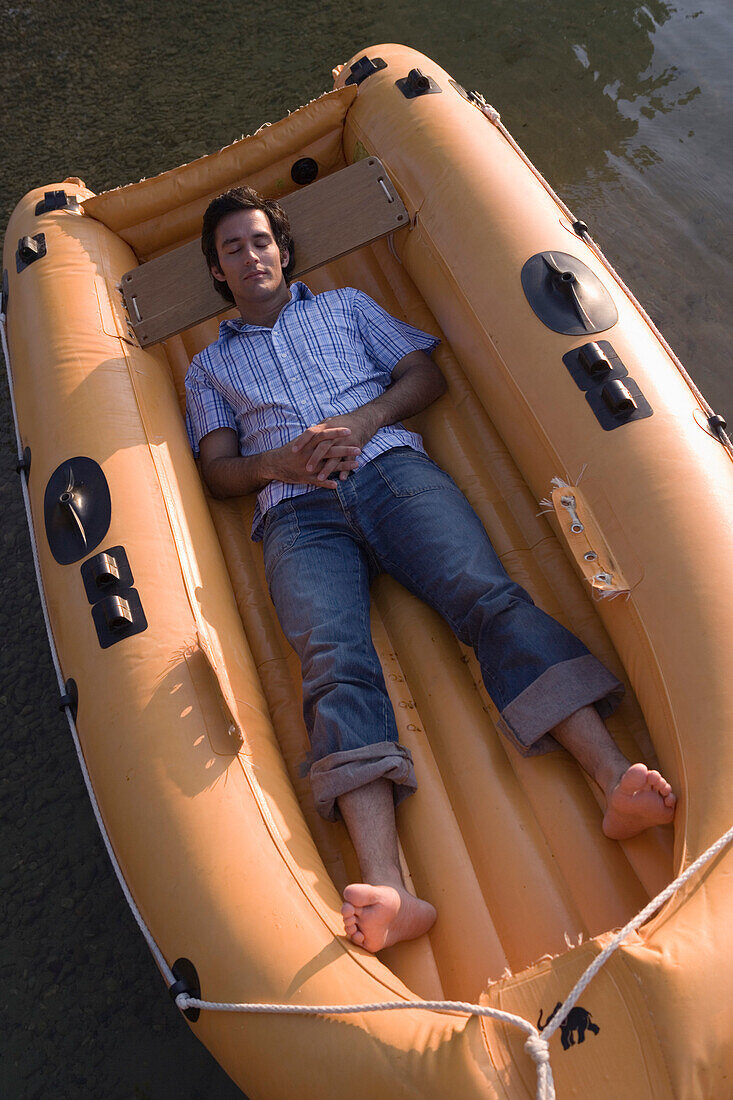 Young man lying in dinghy