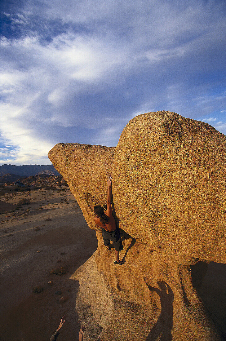 Man bouldering under clouded sky, Tafraout, Morocco, Africa