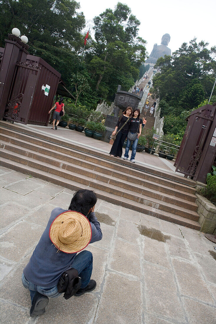 Mann fotografiert Touristen bei der riesigen Tian Tan Buddhastatue, Ngong Ping Plateau, Lantau Island, Hong Kong