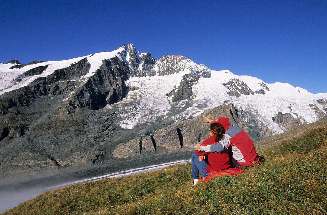 Two hikers in front of the Pasterze glacier and Grossglockner, Glockner range, Hohe Tauern national park, Carinthia, Austria