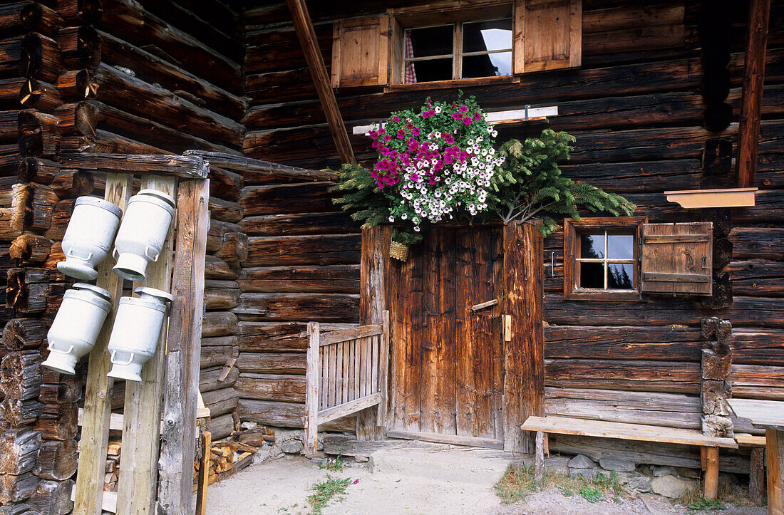 Milk cans and door with flower decorations, Pehab hut, Dachstein mountain range, Salzburg, Austria