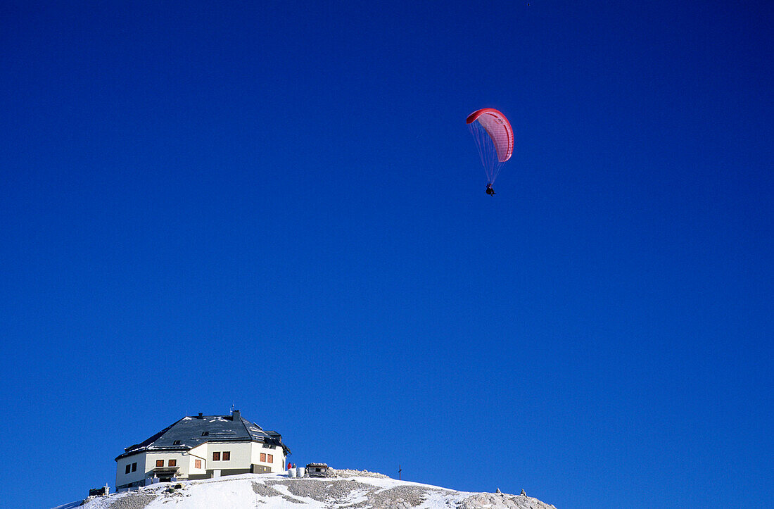 Paraglider above Matrashaus on the summit of Hochkoenig, Berchtesgaden range, Salzburg, Austria