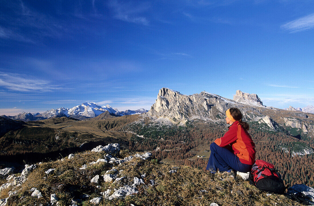 Hiker resting at Monte Formin with view to Marmolada, Averau and Nuvolau, Dolomites, Cortina, Venezia, Italy