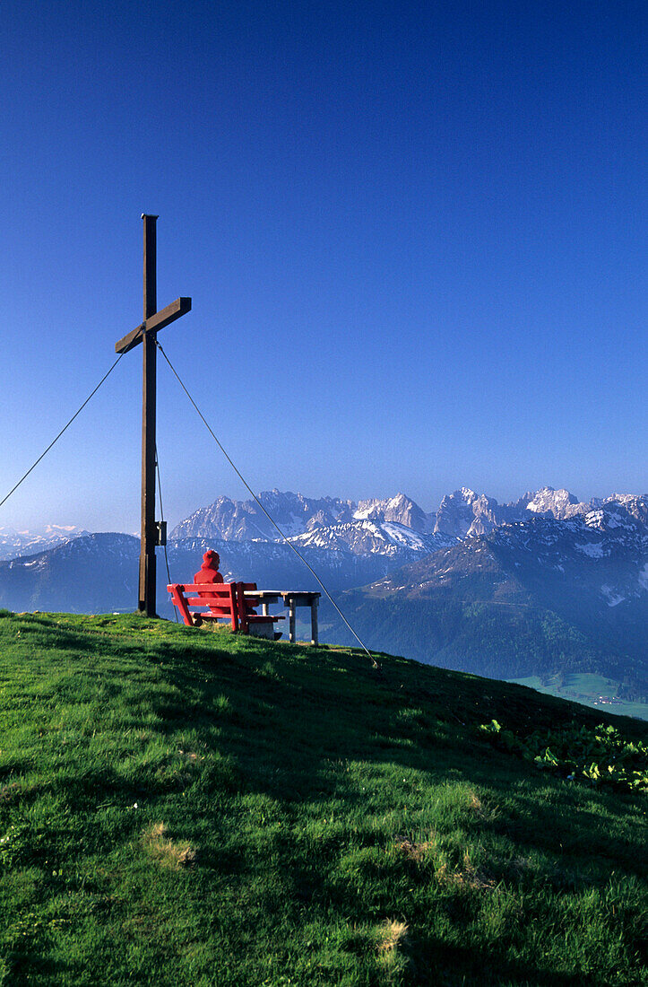 Hiker resting on the summit of Wandberg with view to Wilder Kaiser, Chiemgau alps, Tyrol, Austria