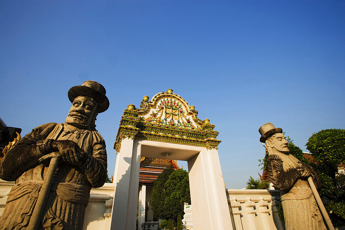 Temple guards next to a gate of Wat Pho, The Temple of the Reclining Buddha, the largest and oldest wat in Bangkok, Bangkok, Thailand