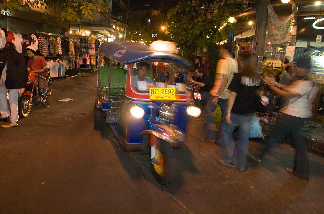Tuk Tuk passing Th Khao San Road in the evening, Banglamphu, Bangkok, Thailand