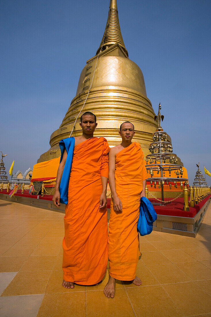 Two monks in front of gilded Chedi, housed a Buddha relic of the Wat Saket on the Golden Mount, Bangkok, Thailand