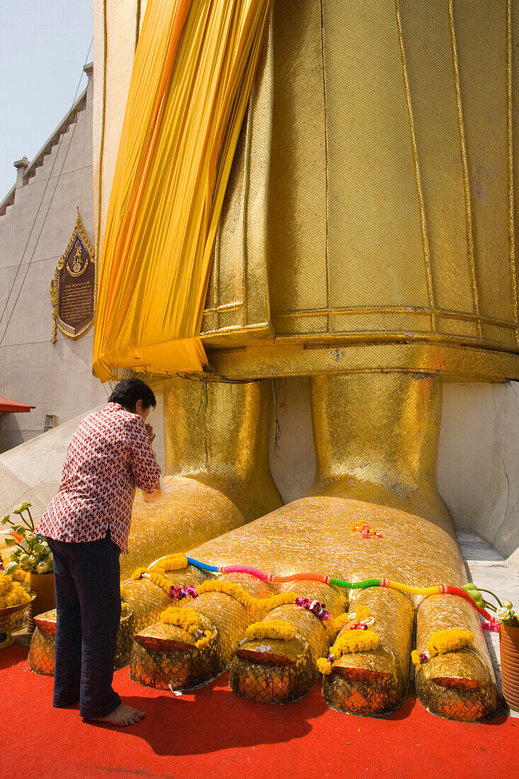 Frau betet am Fuß einer goldenen Buddha-Statue, Wat Intharawihan, Banglamphu, Bangkok, Thailand