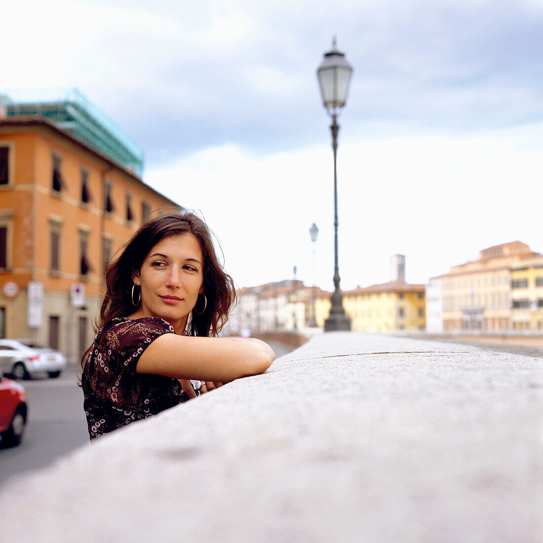 Portrait, Frau in Pisa, Italien, jung, dunkle haare, lange haare, strassenszene, mauer, laterne, steht an mauer, zurückschauen, bunte häuser, fluss arno