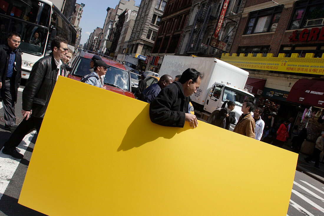 Man carrying yellow board, Canal Street, Trebeca, Chinatown, Manhattan, New York City, New York, United States of America, U.S.A.