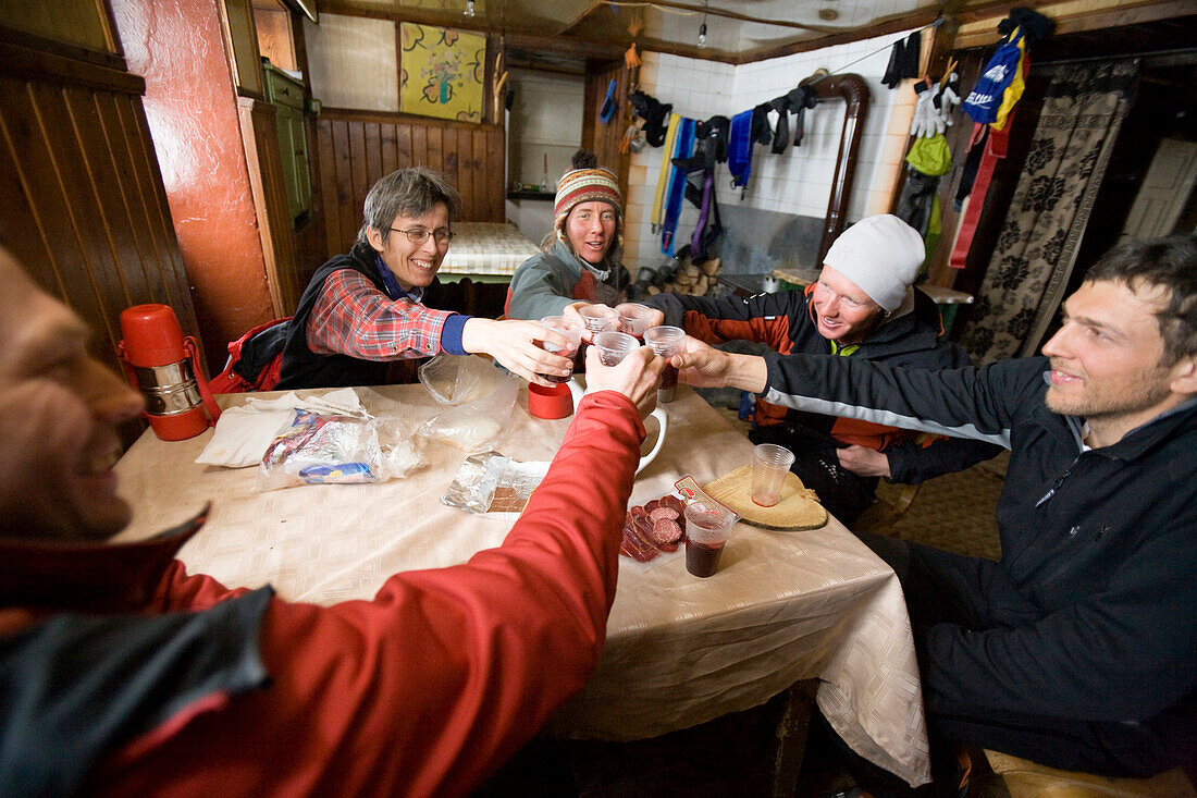 A group of people in a moutain hut toasts with a glass of Raki brandy, Demjanica hut, Pirin Mountains, Bulgaria, Europe