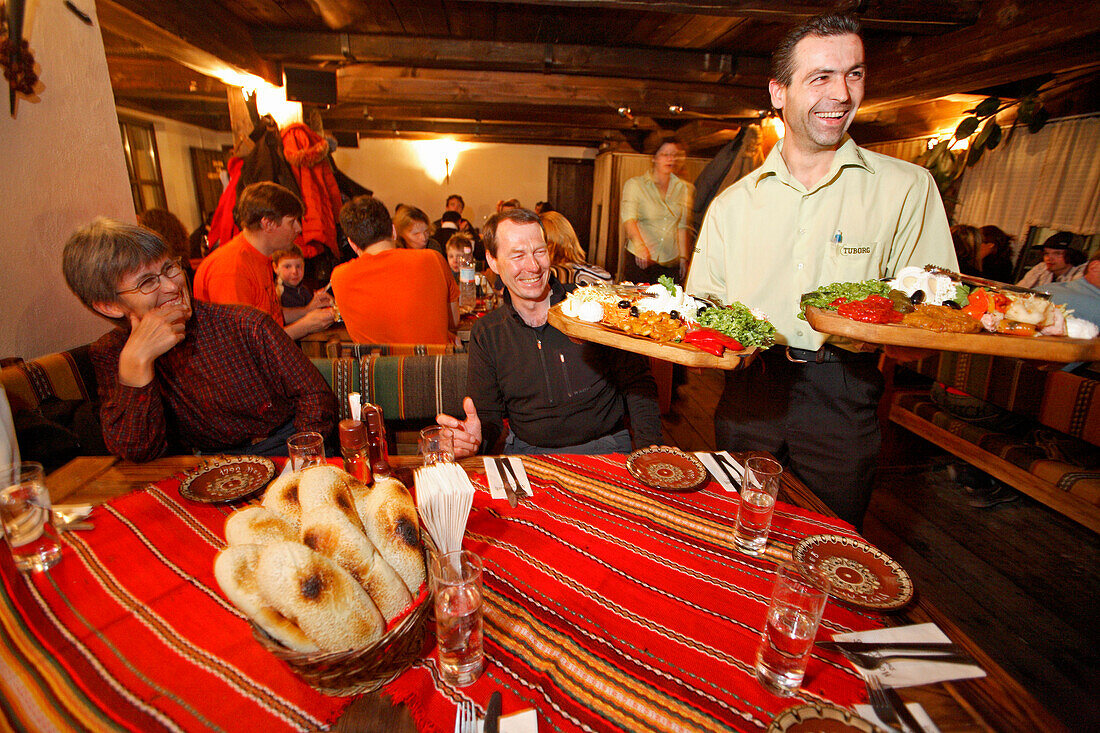 Ein Kellner serviert eine typische bulgarische Salatplatte zur Vorspeise in einem Restaurant in Bansko, Bulgarien