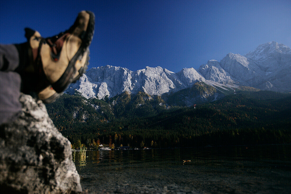 Put your feet up, man resting on the shore of Lake Eibsee, Zugspitze in the background, Bavaria, Germany