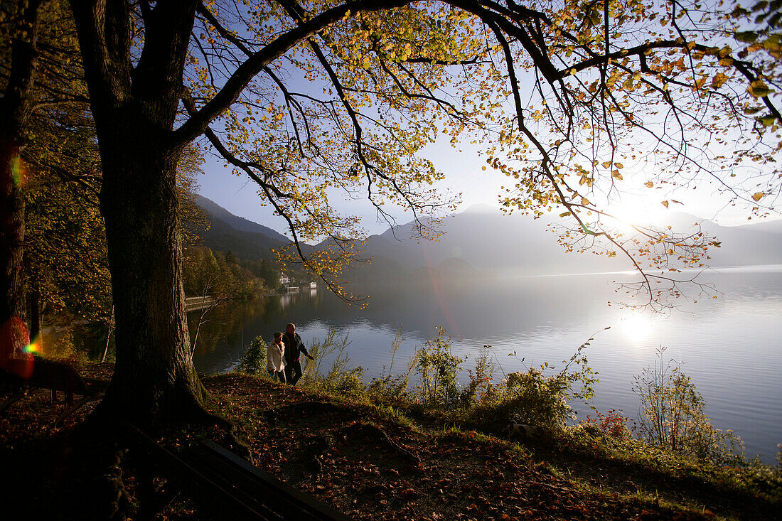 Ein Paar spaziert entlang der Seeufer am Kochelsee in Herbst, Bayern, Deutschland