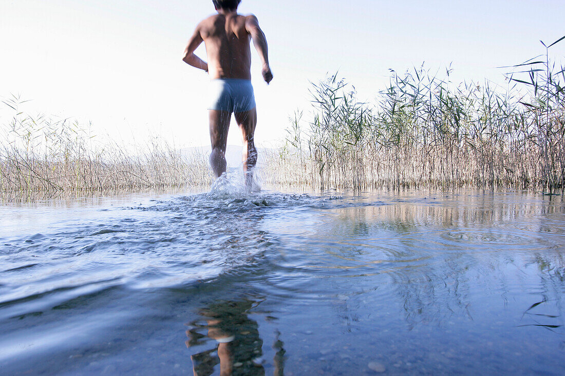 Male swimmer running into the water, Lake Staffelsee, Bavaria, Germany