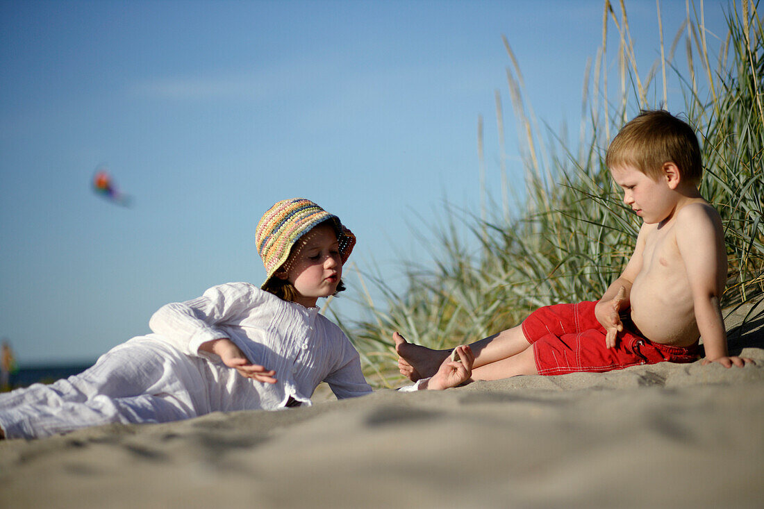 Girl and boy playing at sandy beach of Baltic Sea, Travemuende Bay, Schleswig-Holstein, Germany