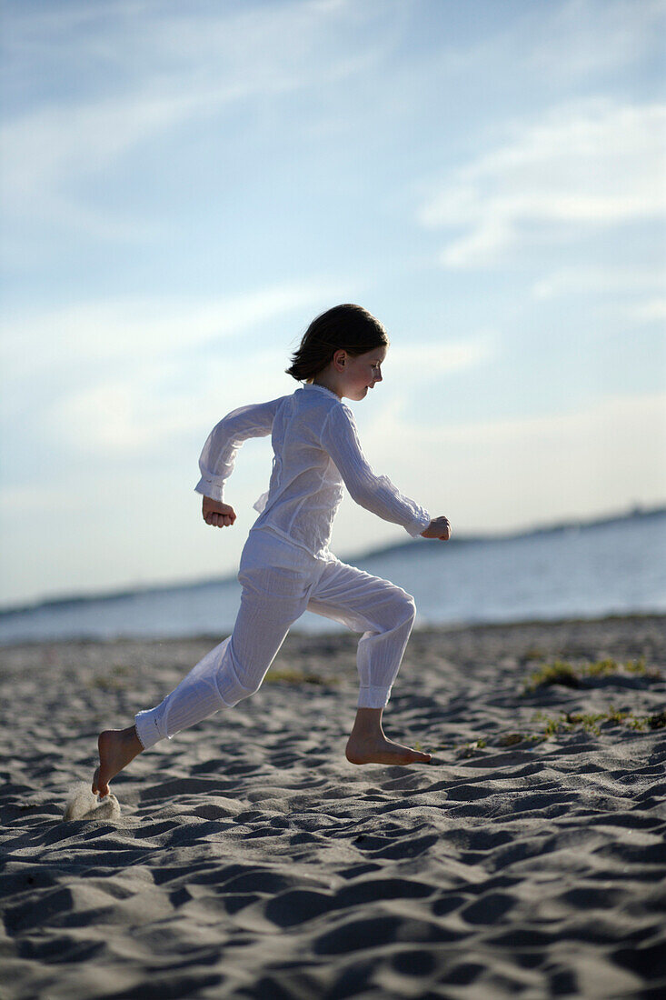 Girl running over sandy beach at Baltic Sea, Travemuende Bay, Schleswig-Holstein, Germany