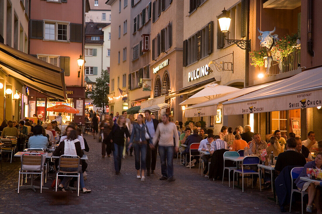 People strolling over Hirschpaltz, passing different pavement cafes and restaurants in the evening (right hand: Restaurant Swiss Chuchi of the Hotel Adler), Niederdorfstrasse, Zurich, Canton Zurich, Switzerland