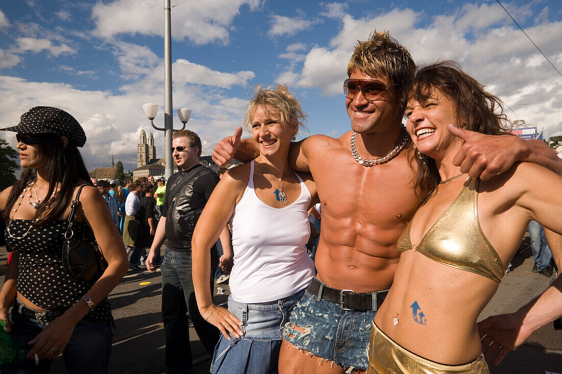 Muscular shirtless man with arms around two young women smiling at camera, Street Parade (the most attended technoparade in Europe) near Quai Bridge, Zurich, Canton Zurich, Switzerland