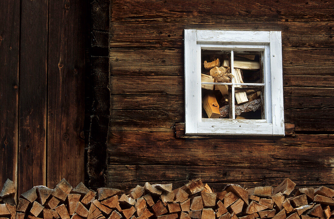 Fenster mit Holzstoß, Detail an einem Bauernhof im Defreggental, Osttirol, Österreich