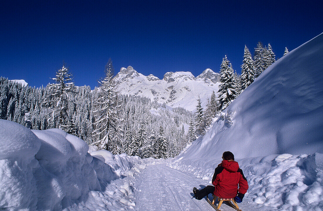 Person sledging on toboggan-run of Sportalm Strussing, view to Tennengebirge range, skiing area Werfenweng, Salzburg, Austria