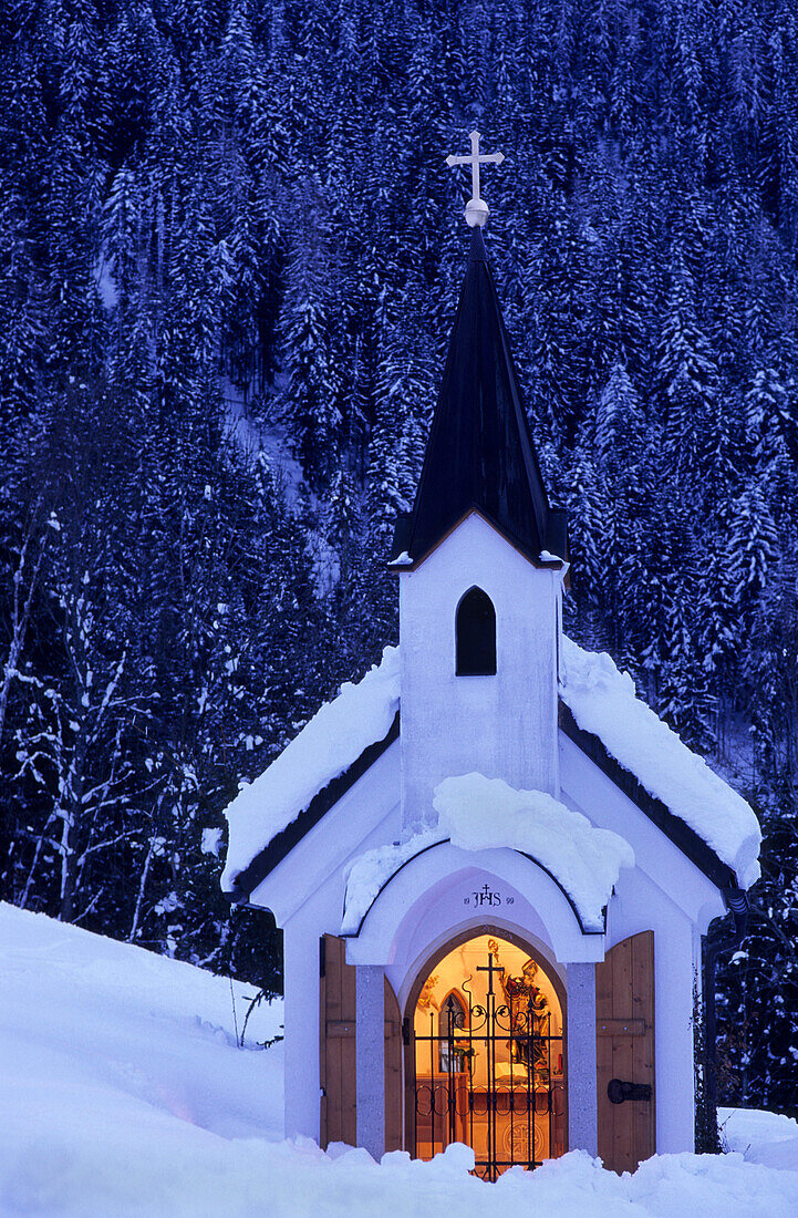 Verschneite beleuchtete Kapelle in der Abenddämmerung, Alpendorf, St. Johann im Pongau, Salzburg, Österreich