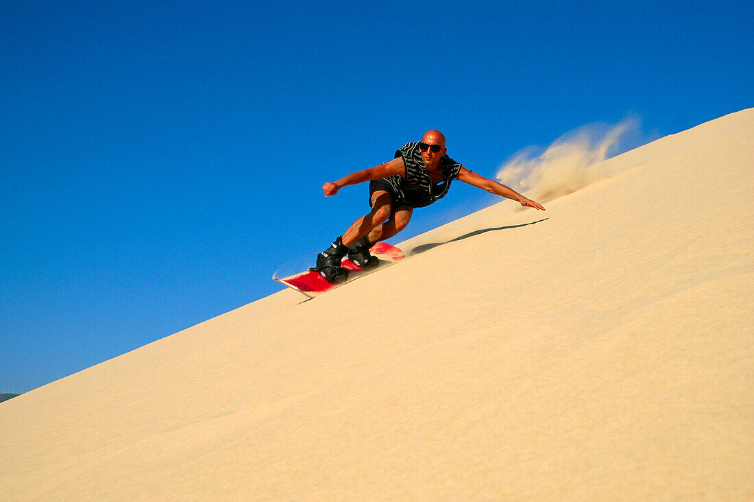 A man sandboarding down a sanddune, Tarifa, Andalusia, Spain, Europe