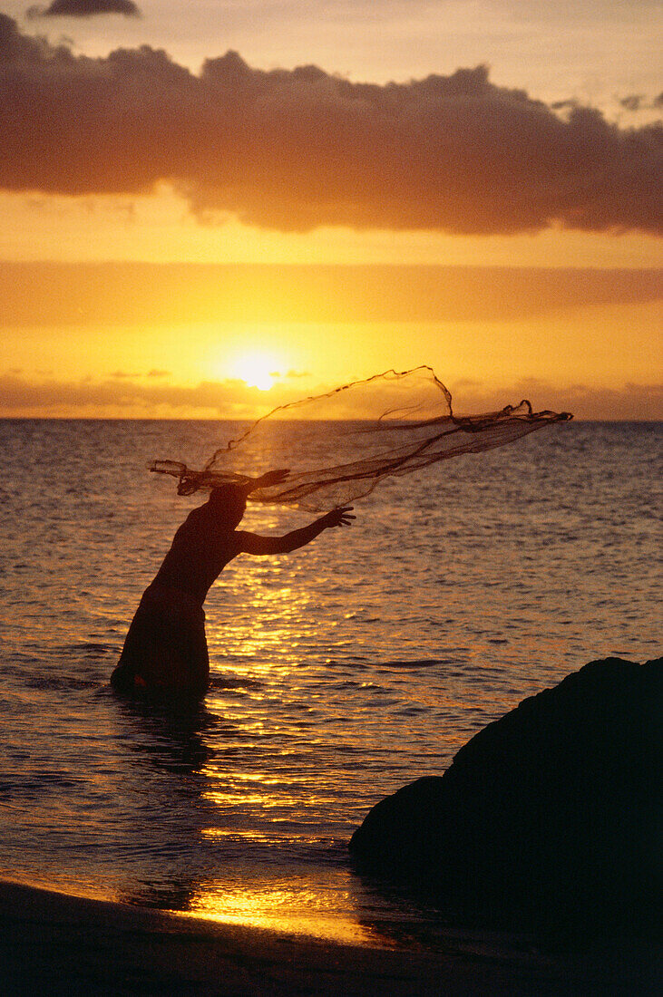 A fisherman throwing out a net at sunset, Fiji, Asia