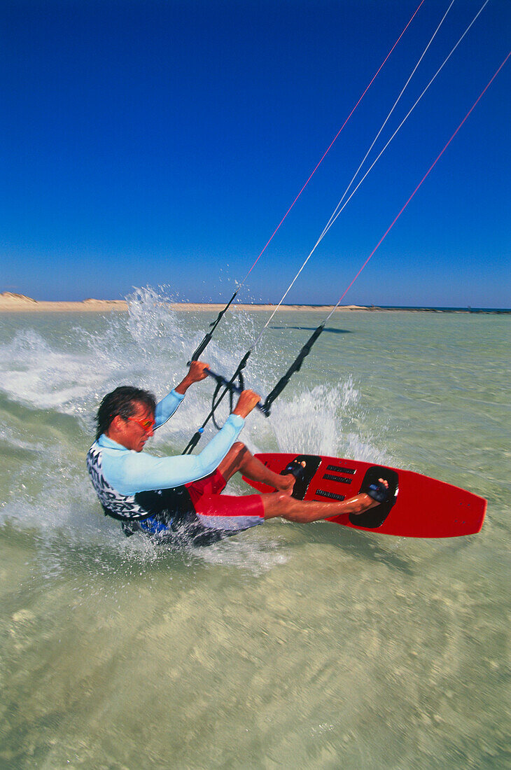 Man kiteboarding at great speed, gripping line with two hands