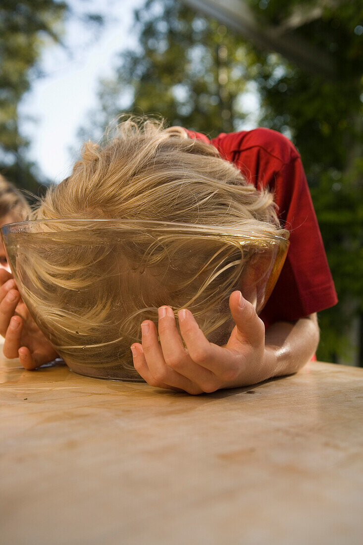 Junge steckt Kopf in eine Schüssel mit Wasser, Kindergeburtstag
