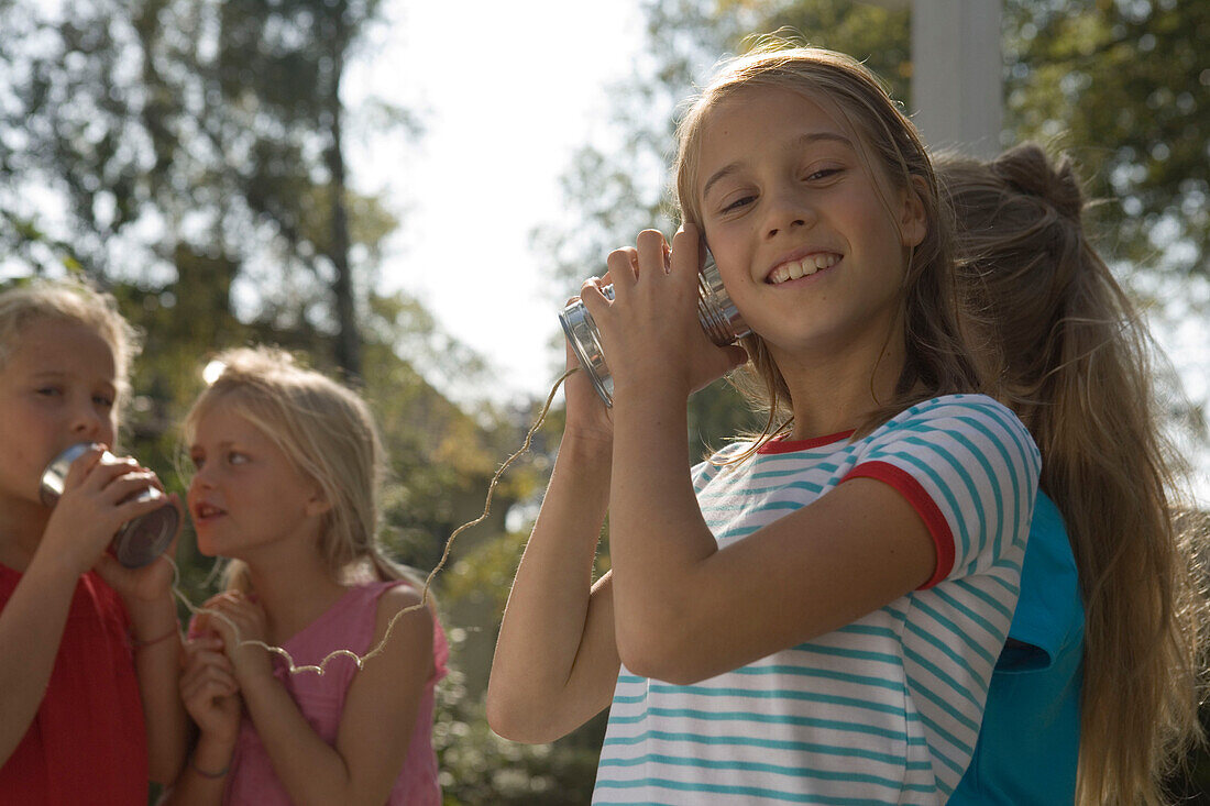 Four girls playing with a tin can phone, children's birthday party