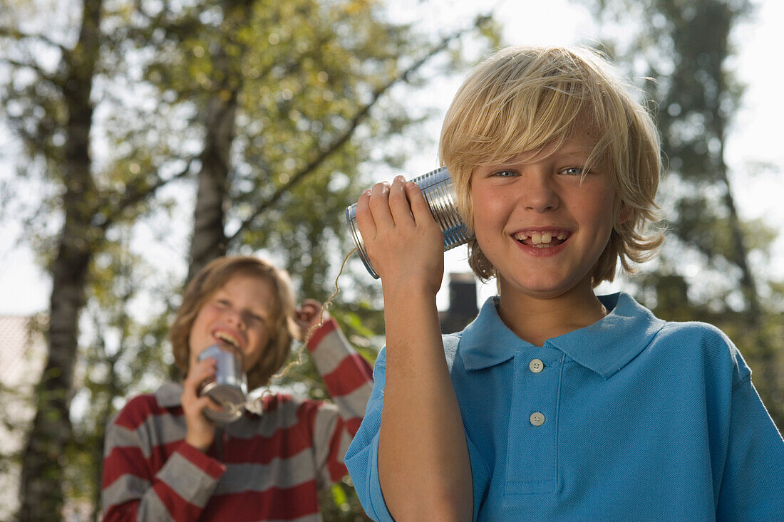 Two boys playing with a tin can phone, children's birthday party