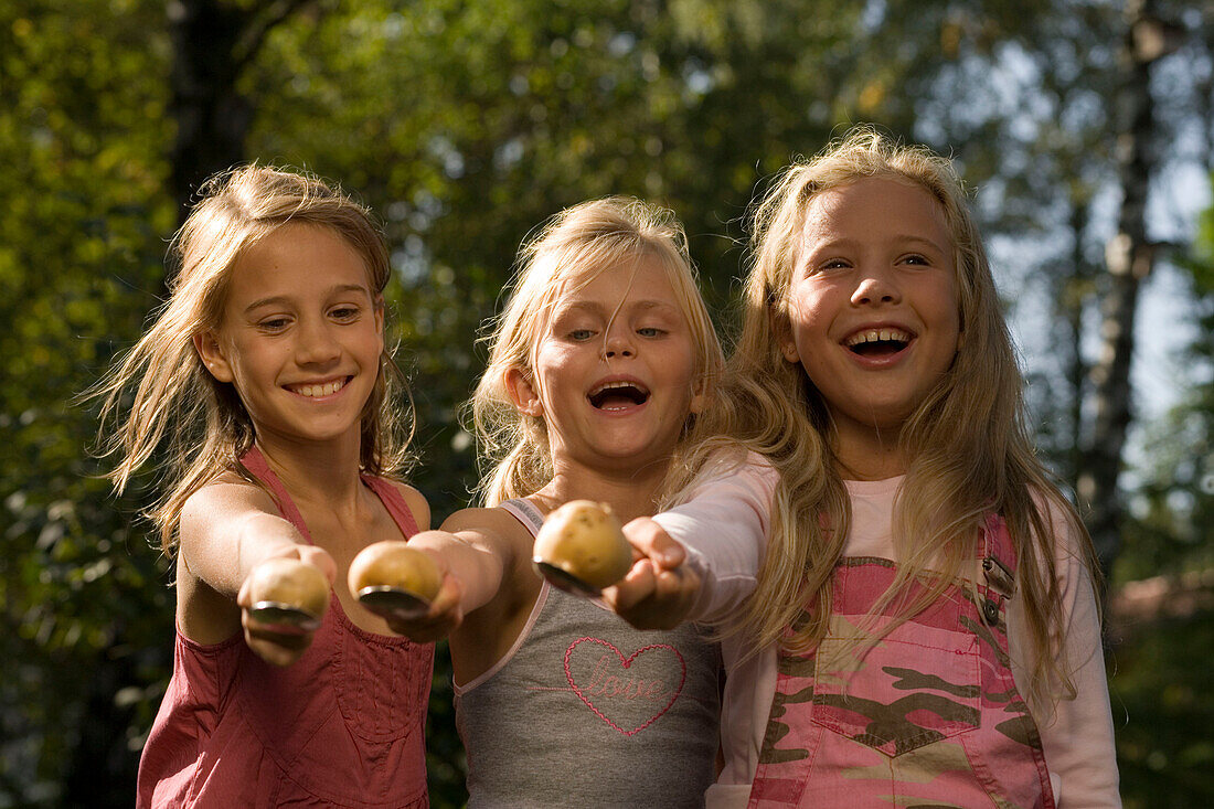 Three girls playing egg-and-spoon race, children's birthday party