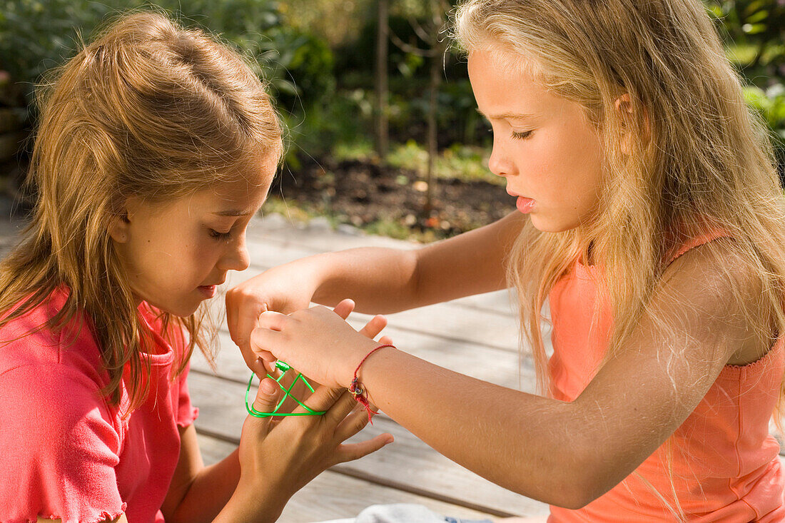 Two girls playing cat's cradle, children's birthday party