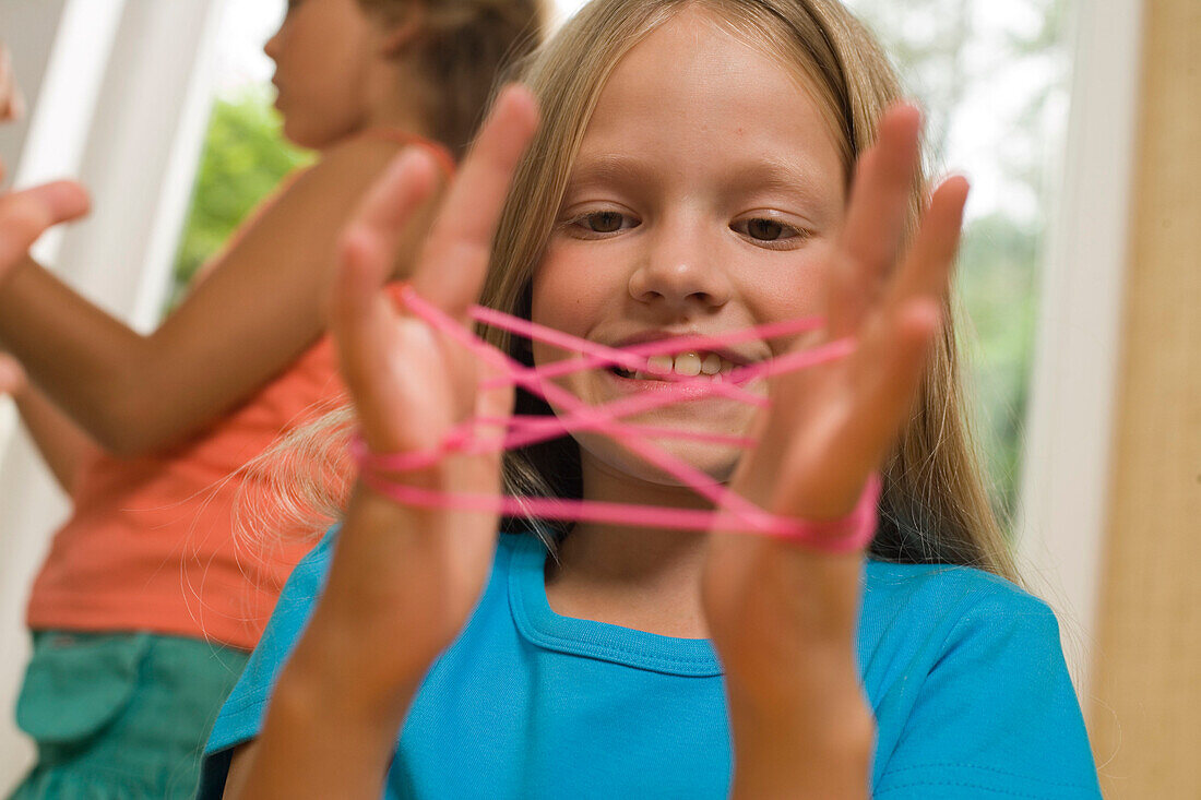Girl playing cat's cradle, children's birthday party