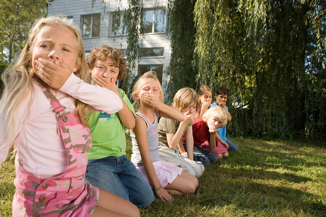 Children crouching on grass and making grimaces, children's birthday party