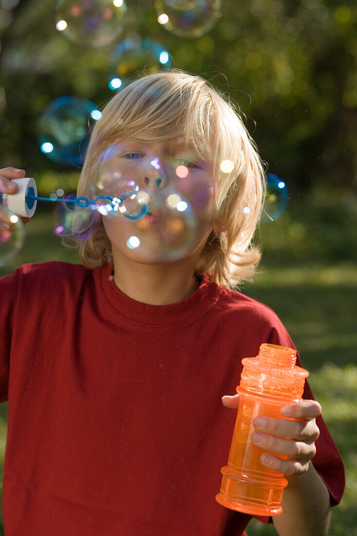 Boy blowing soap bubbles, children's birthday party
