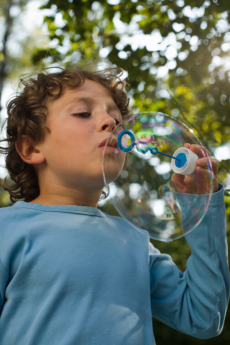 Boy blowing soap bubbles, children's birthday party