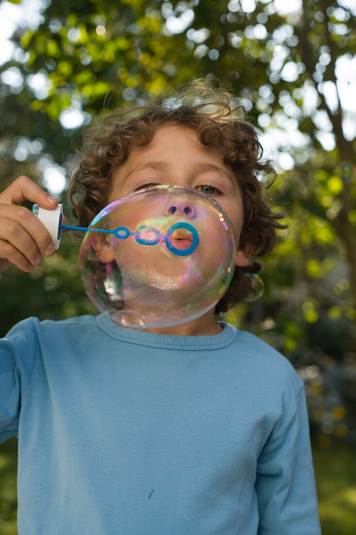 Boy blowing soap bubbles, children's birthday party