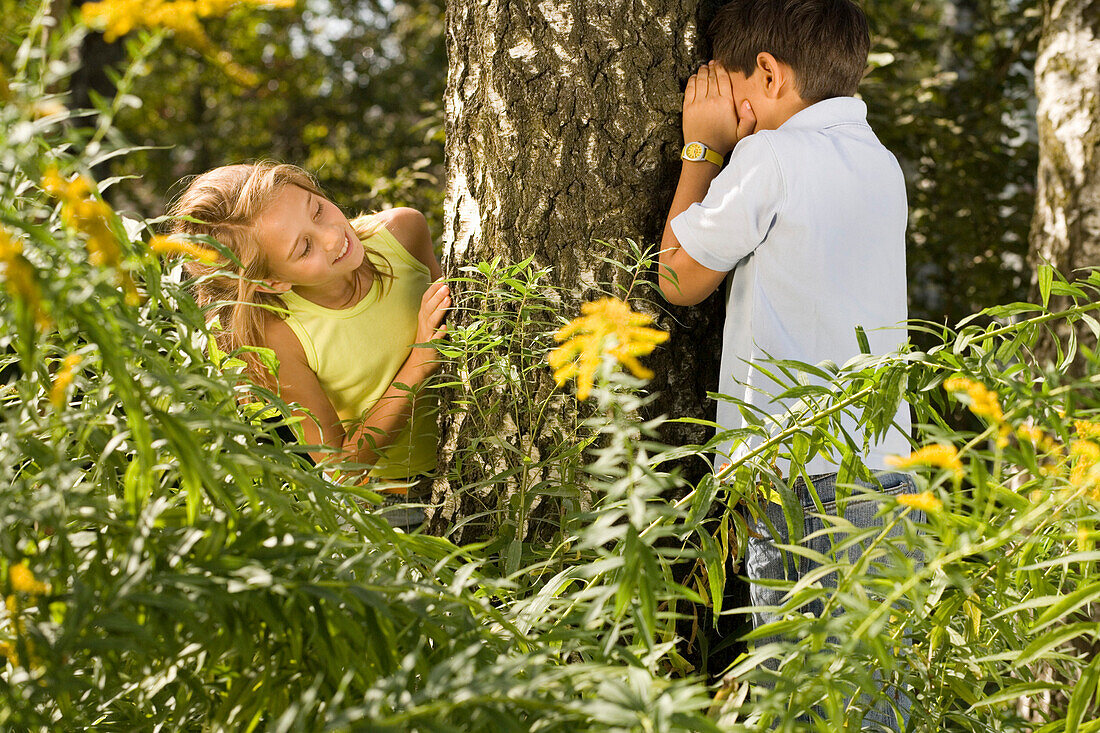 Girl and boy playing hide-and-seek, children's birthday party