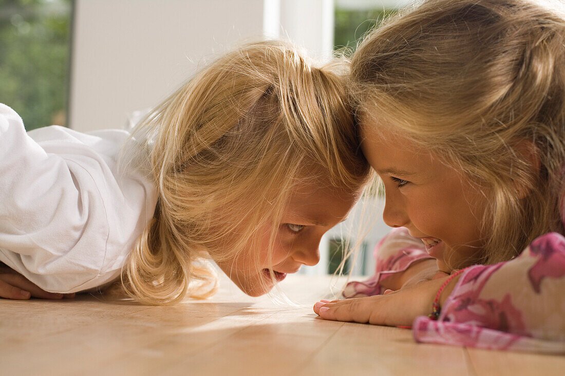 Zwei Mädchen sitzen sich Kopf an Kopf gegenüber, Kindergeburtstag