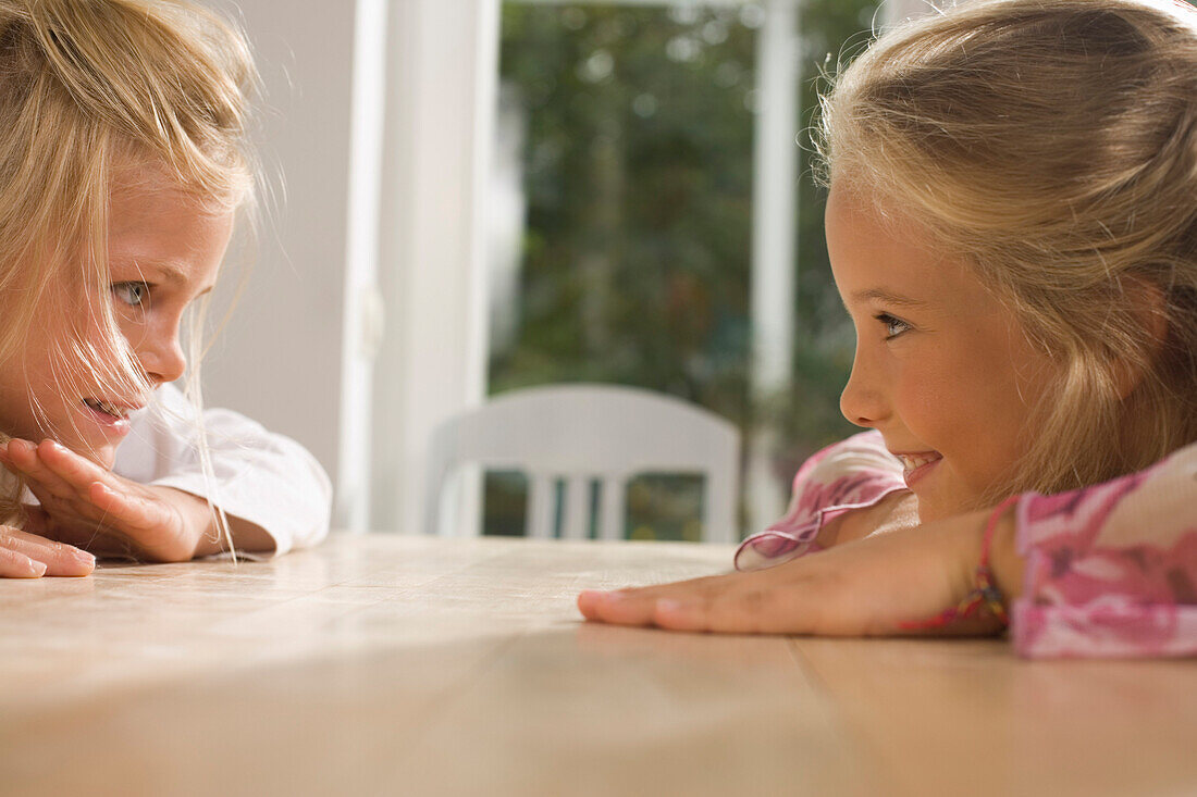 Zwei  Mädchen sitzen sich an einem Tisch gegeüber, Kindergeburtstag