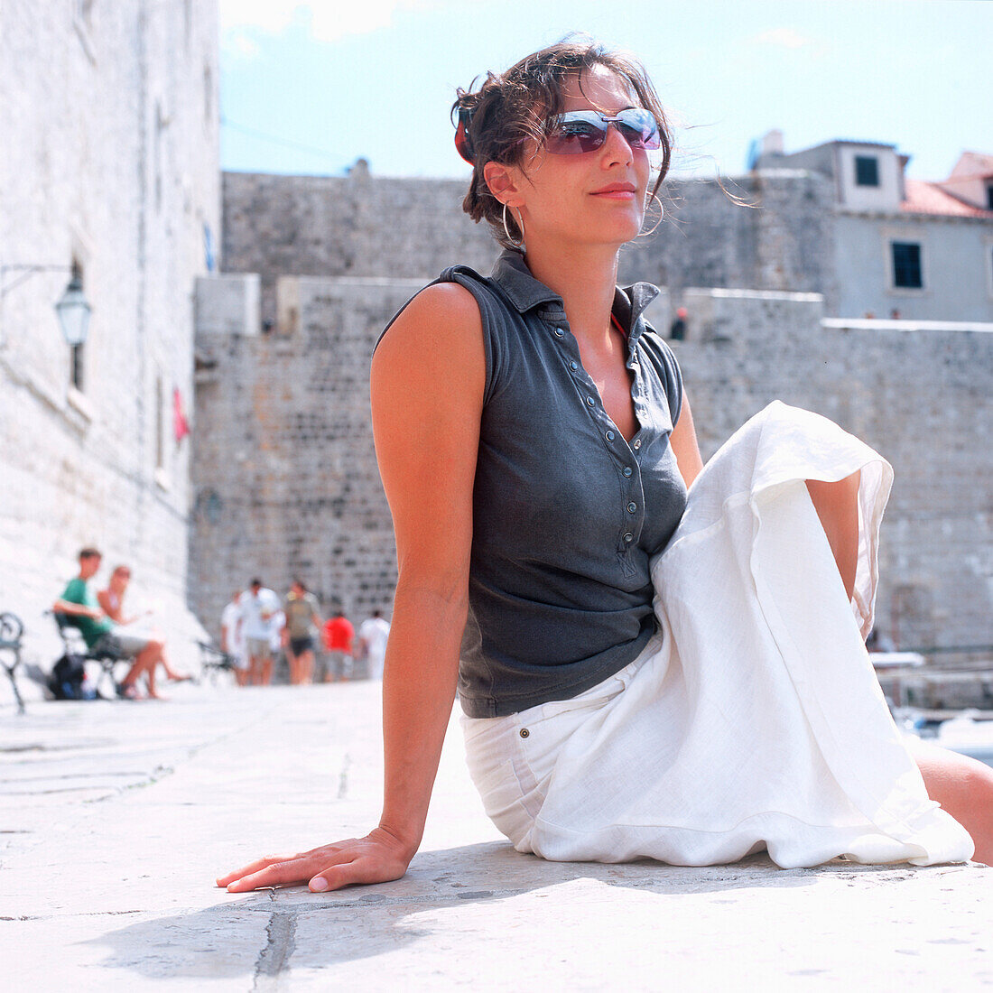 Female tourist sitting at harbour near city wall, Dubrovnik, Dalmatia, Croatia