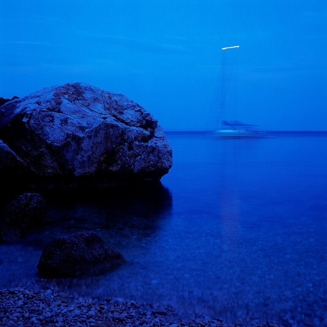 Fels liegt am Ufer der Adria, Segelboot im Hintergrund, Dalmatien, Kroatien