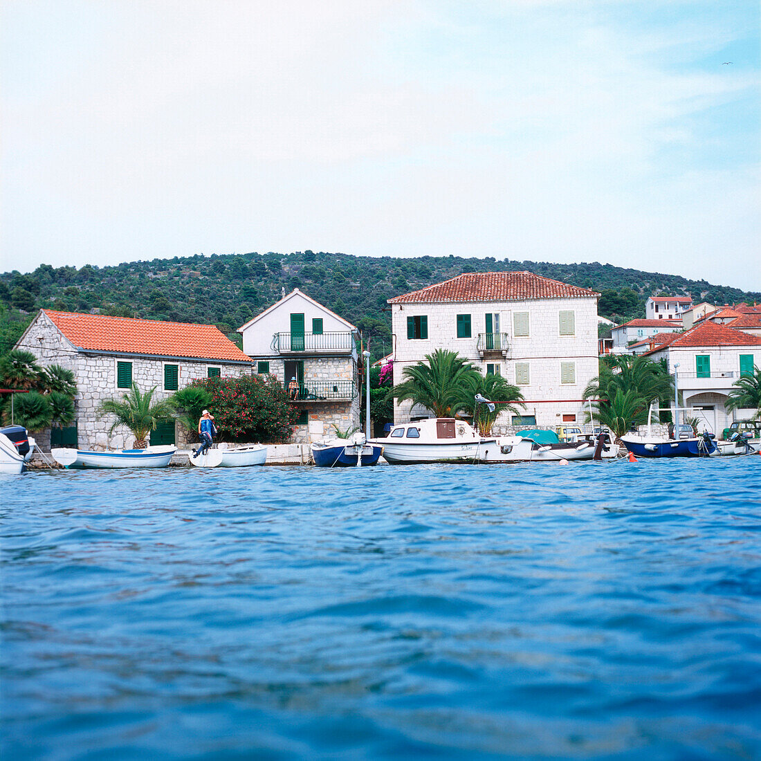Blick über die Adria auf alte Steinhäuser und kleine Boote, Stari Grad, Hvar, Dalmatien, Kroatien