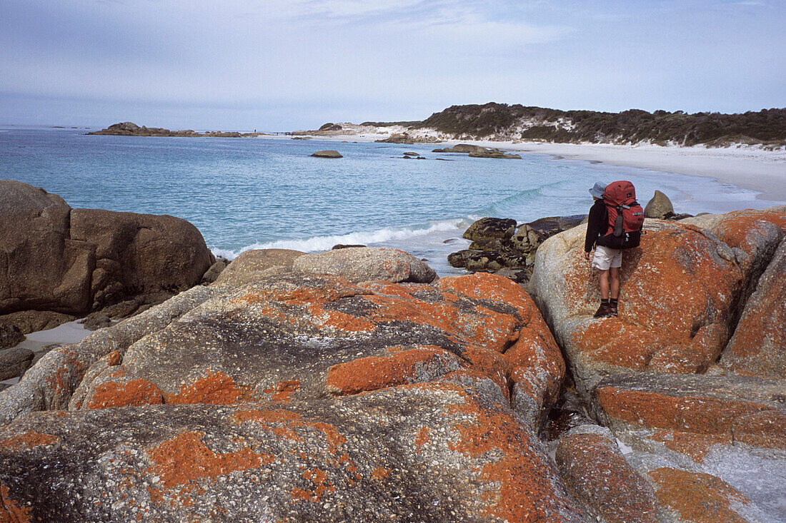 Ein Wanderer und eine felsige Küstenlandschaft, Bay of Fires Walk, Tasmanien, Australien