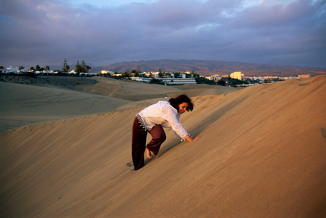 Woman climbing up a dune, Maspalomas, Gran Canaria, Spain