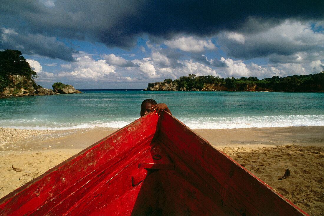 Junge und ein rotes Boot am Boston Beach, Dragon Bay, Provinz Portland, Jamaika, Karibik